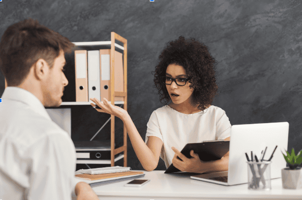 una psciologa e un paziente; seduti; scrivania;